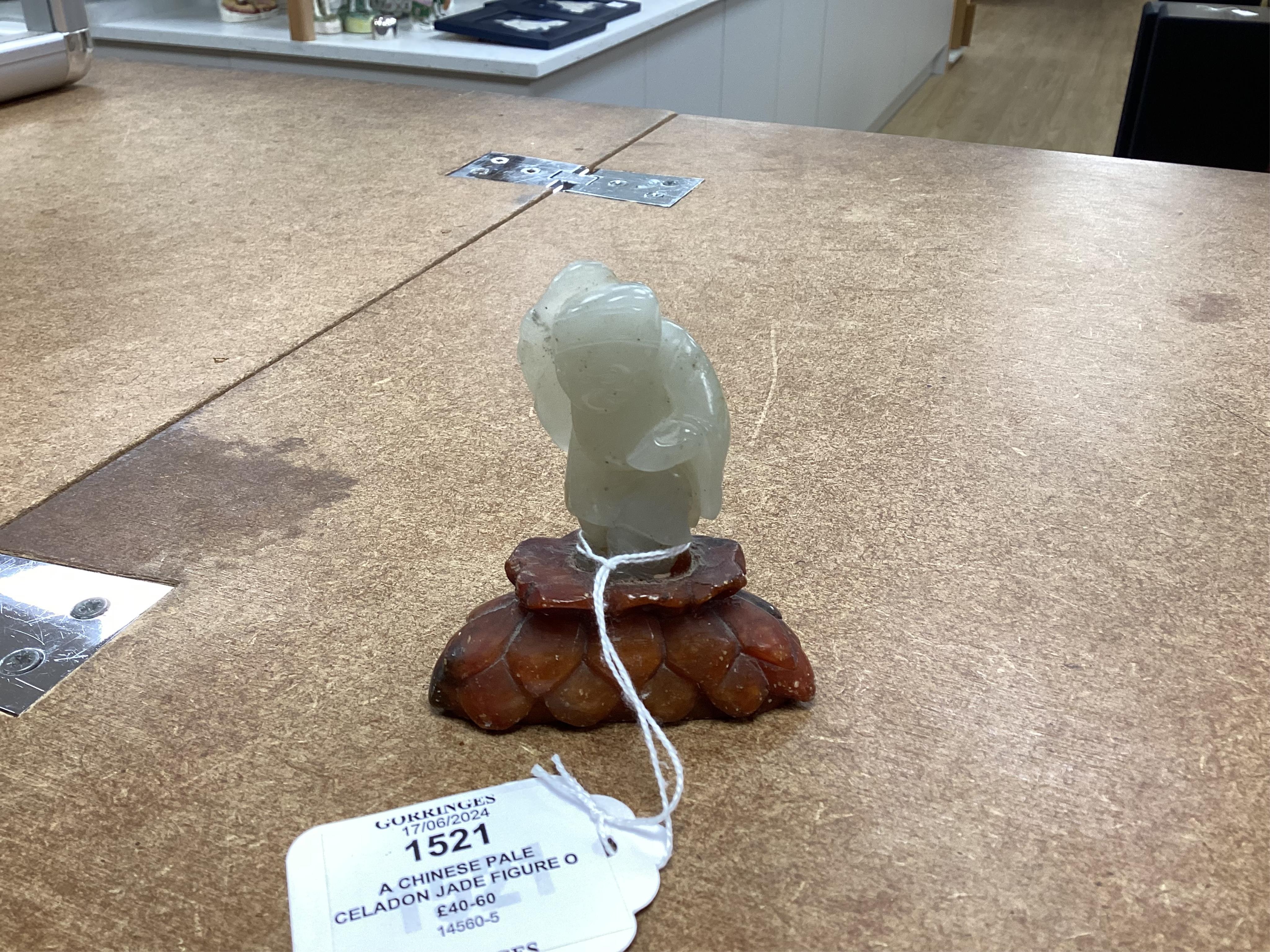 A Chinese pale celadon jade figure of a man holding a fly whisk, Qing dynasty, 5.2cm high, soapstone stand, total height 8cm high